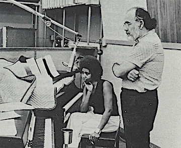 Aretha Franklin seated beside a piano with Jerry Wexler standing in a recording studio